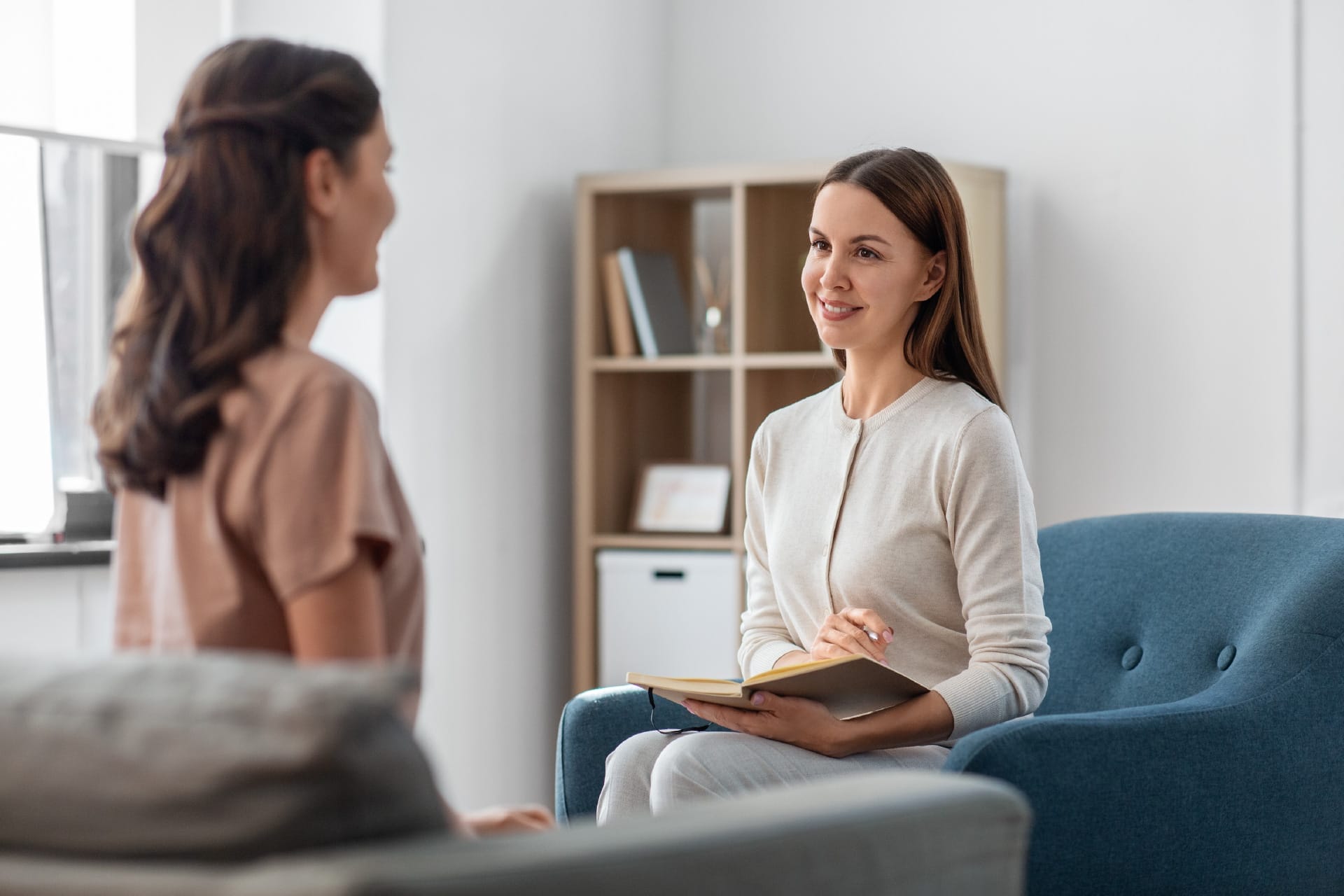 Two women facing each other, sitting on opposite couches