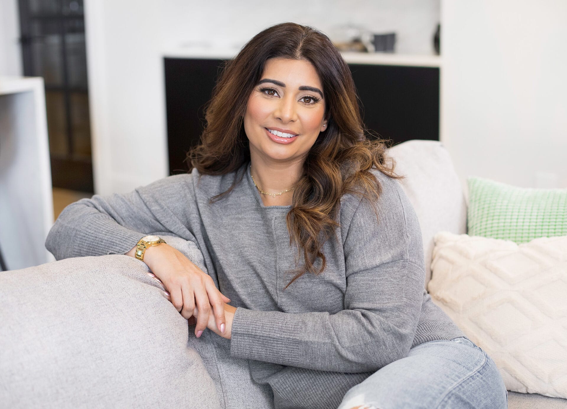 Jas Hundal on Couch and Smiling at Camera