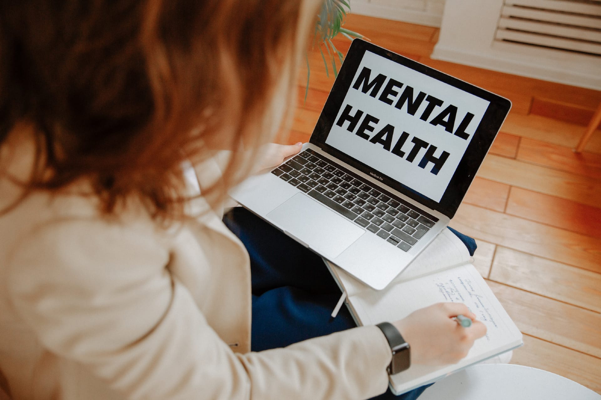 A woman looking at a laptop that reads "Mental Health"